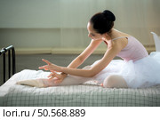 A girl ballet student, Warm up in bed in bedroom before practicing ballet at home. Стоковое фото, агентство Ingram Publishing / Фотобанк Лори
