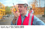 Portrait of crane worker on construction crane use walkie talkie to talk for made to transport the crane from storage to be assembled on the building construction site. Стоковое фото, агентство Ingram Publishing / Фотобанк Лори