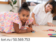 On a holiday, A woman and her little daughters sit on the floor and drawing together in the living room. Стоковое фото, агентство Ingram Publishing / Фотобанк Лори