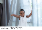 A tiny girl plays hide-and-seek with drapes in her bedroom. Стоковое фото, агентство Ingram Publishing / Фотобанк Лори
