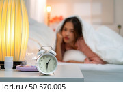 Asian young woman on the bed in the bedroom trying to wake up and prepare for work. Стоковое фото, агентство Ingram Publishing / Фотобанк Лори