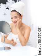 Asian young woman with towel wrapped on head and body applying makeup after shower, Morning beauty routine before work. Стоковое фото, агентство Ingram Publishing / Фотобанк Лори