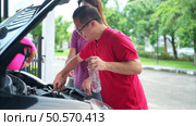 A brother and sister help each other execute a basic engine check on their parents’ automobile. Стоковое фото, агентство Ingram Publishing / Фотобанк Лори