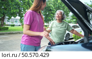 Grandmother and grandchild help each other execute a basic engine check on their parents’ automobile. Стоковое фото, агентство Ingram Publishing / Фотобанк Лори