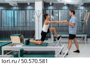 A young man and a young woman are doing pilates exercises on a pilates reformer. Стоковое фото, агентство Ingram Publishing / Фотобанк Лори