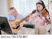 A girl violinist and her grandfather practice music together at home. Стоковое фото, агентство Ingram Publishing / Фотобанк Лори