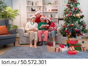 Family members are exchanging gifts with each other during the Christmas holiday at home. Стоковое фото, агентство Ingram Publishing / Фотобанк Лори