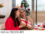 Family members are exchanging gifts with each other in the dinner time during the Christmas holiday at home. Стоковое фото, агентство Ingram Publishing / Фотобанк Лори