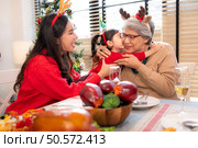 A little granddaughter lovingly hugs her grandmother, while they eating a meal together during the Christmas celebration at home. Стоковое фото, агентство Ingram Publishing / Фотобанк Лори