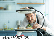 A young man puts on an apron to make dessert to eat with his wife. Checking the completeness of the finished dessert. Стоковое фото, агентство Ingram Publishing / Фотобанк Лори