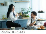 A husband wears an apron while cooking dinner with his wife. The duo took a break to sip coffee and sample the completed bread. Стоковое фото, агентство Ingram Publishing / Фотобанк Лори