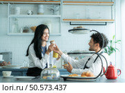 A husband wears an apron while cooking dinner with his wife. The duo took a break to sip coffee and sample the completed bread. Стоковое фото, агентство Ingram Publishing / Фотобанк Лори