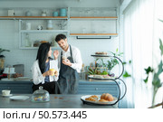 A husband wears an apron while cooking dinner with his wife. The duo took a break to sip coffee and sample the completed bread. Стоковое фото, агентство Ingram Publishing / Фотобанк Лори