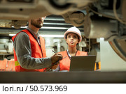 Male and female engineers work together in an electric repair station. Inspecting the undercarriage of electric train that are being repaired at the garage. Стоковое фото, агентство Ingram Publishing / Фотобанк Лори