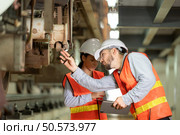 Male and female engineers work together in an electric repair station. Inspecting the undercarriage of electric train that are being repaired at the garage. Стоковое фото, агентство Ingram Publishing / Фотобанк Лори