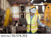Railway technician in uniform and helmet inspect the train wheels removed from the locomotives in the train workshop. Стоковое фото, агентство Ingram Publishing / Фотобанк Лори