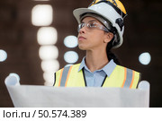 Portrait of railway technician worker in safety vest and helmet working with blueprint at train repair station. Стоковое фото, агентство Ingram Publishing / Фотобанк Лори