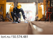 Railway technician in uniform and helmet inspect the train wheels removed from the locomotives in the train workshop. Стоковое фото, агентство Ingram Publishing / Фотобанк Лори