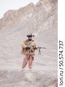A Taliban soldier stands with a machine gun, In the desert mountain landscape. Стоковое фото, агентство Ingram Publishing / Фотобанк Лори