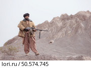 A Taliban soldier stands with a machine gun, In the desert mountain landscape. Стоковое фото, агентство Ingram Publishing / Фотобанк Лори