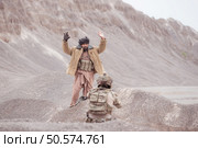 A Taliban soldier stands with a machine gun, Raise hands in surrender to the allied soldiers, In the desert mountain terrain battlefield. Стоковое фото, агентство Ingram Publishing / Фотобанк Лори