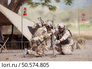 Group of soldiers in camouflage uniforms hold weapons in front of camp tent, Plan and prepare for combat training. Стоковое фото, агентство Ingram Publishing / Фотобанк Лори