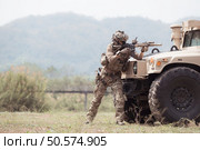 Soldiers in camouflage uniforms hold weapons ready to fire, By hiding on the side military communication vehicle. Стоковое фото, агентство Ingram Publishing / Фотобанк Лори