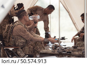 Group of soldiers in camouflage uniforms hold weapons in a field tent, Plan and prepare for combat training. Стоковое фото, агентство Ingram Publishing / Фотобанк Лори