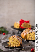 A slice of Bolo Rainha, a Portuguese Christmas cake, is displayed on a black plate with other cakes in the background creating a festive holiday scene. Стоковое фото, агентство Ingram Publishing / Фотобанк Лори