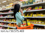 sale, shopping, consumerism, communication and people concept - woman with food basket calling on smartphone at grocery store or supermarket. woman with food basket and smartphone at store. Стоковое фото, агентство Ingram Publishing / Фотобанк Лори