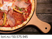 Hot spicy pepperoni pizza with sausage, ham and chilly pepeer served on wood plate. Стоковое фото, агентство Ingram Publishing / Фотобанк Лори