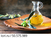 Battle of olive oil with olive branch in handmade clay plate over wooden table. Стоковое фото, агентство Ingram Publishing / Фотобанк Лори