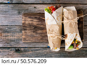Mexican style dinner. Two papered tortillas with beef and vegetables served with nachos chips and guacomole sauce over old wooden background. Flat lay With copy space. Tortillas and nachos. Стоковое фото, агентство Ingram Publishing / Фотобанк Лори