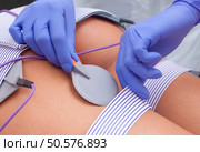 The procedure of myostimulation on the legs and buttocks of a woman in a beauty salon. Caring for the body, reducing excess weight. Стоковое фото, агентство Ingram Publishing / Фотобанк Лори