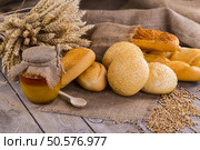 Honey in a jar, slice of bread, wheat and milk on an old vintage planked wood table from above. Rural or rustic style breakfast concept. Background layout with free text space. Стоковое фото, агентство Ingram Publishing / Фотобанк Лори