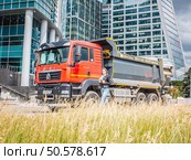 HOWO dump truck parked against the backdrop of modern glass office buildings in the city. Редакционное фото, фотограф Константин Григорьев / Фотобанк Лори