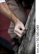 Grabing onto a small handhold, a climber makes his way to the top. His hand is covered in chalk, and there is a very shallow depth of field. Стоковое фото, агентство Ingram Publishing / Фотобанк Лори