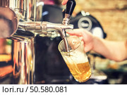 barman hand at beer tap pouring a draught lager beer serving in a restaurant or pub. Стоковое фото, агентство Ingram Publishing / Фотобанк Лори