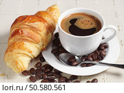 Cup of hot coffee and croissant on table covert tablecloth. Стоковое фото, агентство Ingram Publishing / Фотобанк Лори