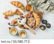 Breakfast with croissants, homemade ricotta cheese, figs, fresh berries, prosciutto, honey and espresso coffee on rustic serving board over white marble background, top view, horizontal composition. Breakfast with croissants, ricotta, coffee and berries over white background. Стоковое фото, агентство Ingram Publishing / Фотобанк Лори