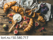 Breakfast with freshly baked croissants, ricotta cheese, figs, fresh berries, prosciutto di Parma and honey in glass jar over rustic wooden background, top view, horizontal composition. Croissants, ricotta cheese, figs, fresh berries, prosciutto and honey. Стоковое фото, агентство Ingram Publishing / Фотобанк Лори