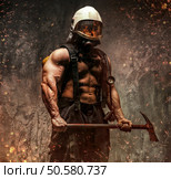 Brutal muscular firefighter holding safety axe in fire sparks over grey background. Стоковое фото, агентство Ingram Publishing / Фотобанк Лори