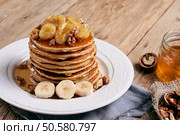 Closeup delicious and healthy breakfast of pancakes with honey, nuts and caramelized bananas on wooden surface with copy space. Стоковое фото, агентство Ingram Publishing / Фотобанк Лори