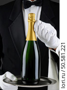 Closeup of a sommelier holding a champagne bottle on a serving tray in front of his torso. Wan is wearing a tuxedo and is unrecognizable. Vertical Format. Стоковое фото, агентство Ingram Publishing / Фотобанк Лори