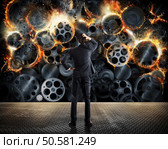 Stress concept with overworked businessman desperately looks a gear mechanism burn. Worn system business problems. Стоковое фото, агентство Ingram Publishing / Фотобанк Лори