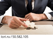Businessman complete a puzzle inserting last piece. Complete a puzzle. Стоковое фото, агентство Ingram Publishing / Фотобанк Лори
