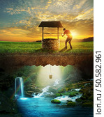 A man lowers a bucket from a well into clear water. Стоковое фото, агентство Ingram Publishing / Фотобанк Лори
