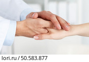 Friendly male doctor’s hands holding female patient’s hand for encouragement and empathy. Partnership, trust and medical ethics concept. Bad news lessening and support. Patient cheering and support. Стоковое фото, агентство Ingram Publishing / Фотобанк Лори