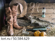 Still life photography with traditional leather boots and american west rodeo brown cowboy hat in vintage ranch barn background. Стоковое фото, агентство Ingram Publishing / Фотобанк Лори