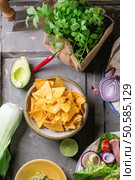 Overhead view on mexican style dinner with tacos, vegetables, nachos chips and guakomole, served over gray wooden table. Стоковое фото, агентство Ingram Publishing / Фотобанк Лори